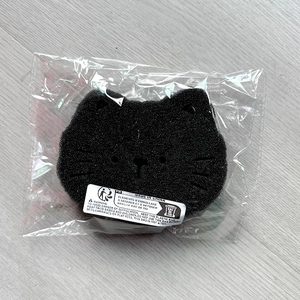 Macro detail of cat-shaped washing machine hair filter sponge in clear plastic packaging