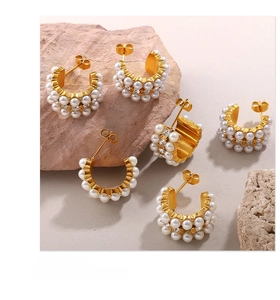 Detail of C-shaped gold earrings with rows of white pearls and sparkling pavé crystals