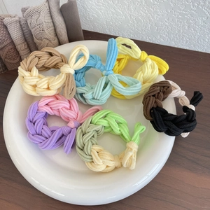 Colorful woven elastic hair ties in various vibrant color combinations on a white tray