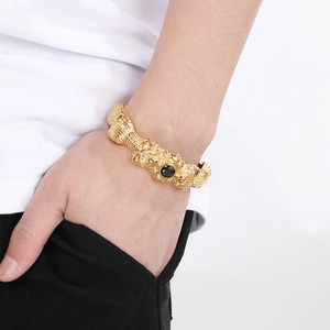 Detailed close-up of golden dragon bangle with black gemstone on male model's wrist