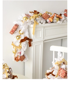 Detail of white Christmas wreath with gold balls, bows and LED lights on a mantel