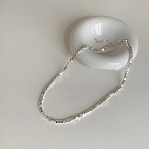 Gros plan d'un collier de perles argentées à facettes avec un éclat métallique brillant