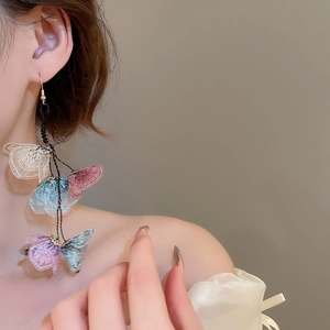 Macro detail of elegant fabric flower tassel earrings with multi-color embroidery on model