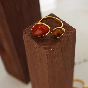 Vintage gold-plated titanium steel ring with red stone and tiger eye on wood stand