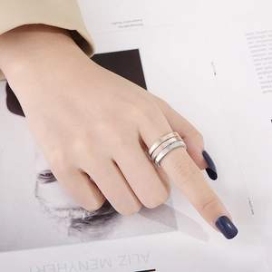 Close-up of three stacked stainless steel rings in gold, rose gold and silver finishes