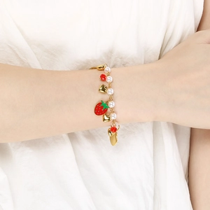Close-up of strawberry pendant bracelet with pearls and golden hearts on a wrist