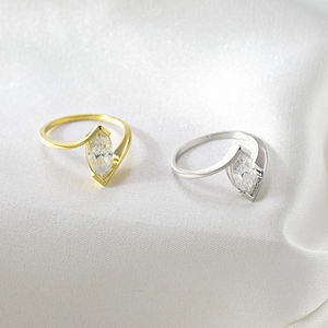 Detail of marquise cut moissanite rings in gold and silver finish on white silk
