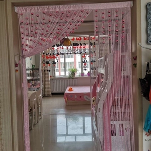 Detailed view of pink string curtain with red floral accents and silver threads for doorways