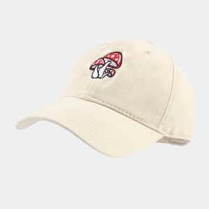 Close-up of red mushroom embroidery on cream cotton baseball cap with detailed stitching