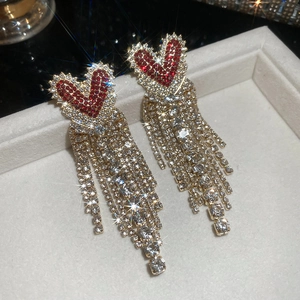 Detail of red rhinestone heart earrings with long crystal tassels on jewelry tray