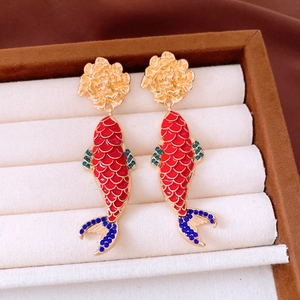 Macro shot of koi fish drop earrings with colorful enamel and crystals in a velvet tray