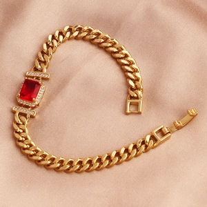 Close-up of a gold-plated bracelet with a red rectangular zircon on rose gold silk fabric
