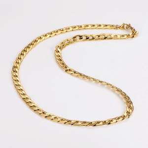 Close-up of golden flat Cuban link chain with polished finish on a white background