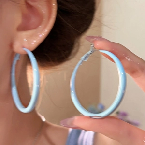Détail de créoles bleu clair avec une finition polie lisse sur un mannequin