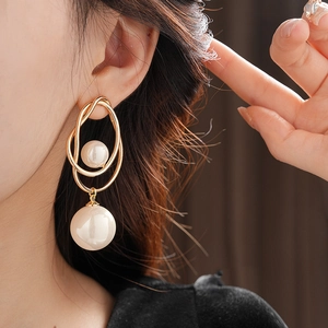 Close-up of gold irregular twisted hoop earrings with layered faux pearls on model