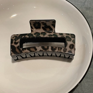 Detail shot of rectangular leopard print hair claw clip in a white ceramic bowl
