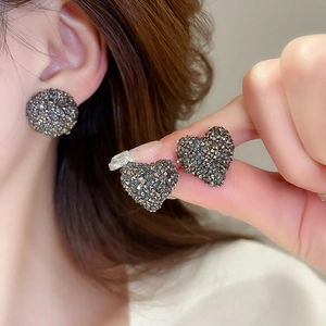 Gros plan de boucles d'oreilles cœur et rondes avec micro-cristaux sombres scintillants