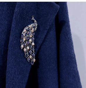 Detailed macro view of a crystal peacock brooch with tassels on a navy wool coat
