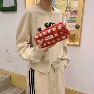 Detail of red and white checkered waffle plush pencil case with zipper and brand label
