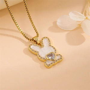 Golden bunny pendant necklace with white enamel and heart zircon on a floral background