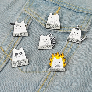 Macro detail of humorous white cat enamel pins with clever slogans on blue denim fabric