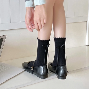 Detail of black frilled socks with ribbon bow back paired with Mary Jane shoes