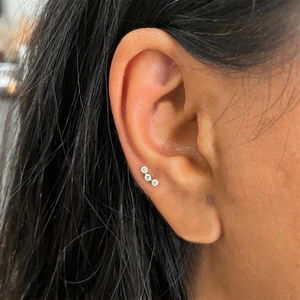 Close-up of a 925 silver cartilage stud with three curved sparkling clear crystals