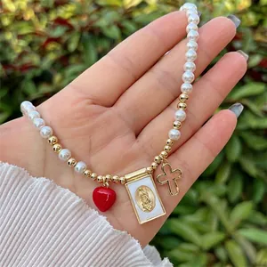 Detail of 18K gold plated pearl necklace with red heart and religious medals