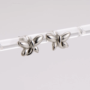 Polished silver stainless steel dragonfly stud earrings displayed on a clear stand