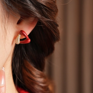 Gros plan d'une boucle d'oreille triangle avec placage or 18k et résine rouge sur modèle