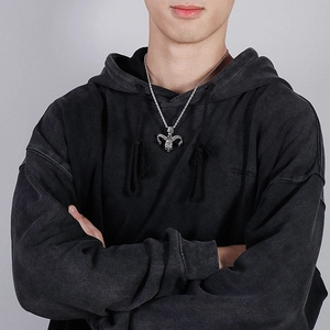 Detailed view of silver goat skull pendant on a twist chain worn over black hoodie