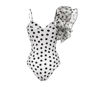 Close-up of ruffled shoulder detail and black polka dots on white one-piece swimsuit