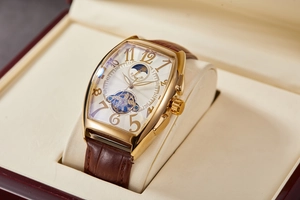 Detail of tonneau mechanical watch with gold case and brown leather strap in luxury box