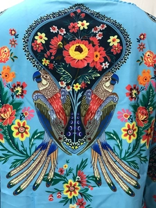 Détail de l'imprimé perroquets et fleurs sur un chemisier bleu ciel