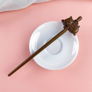 Detail of hand-carved sandalwood hair pin featuring a lucky cat holding a lucky charm