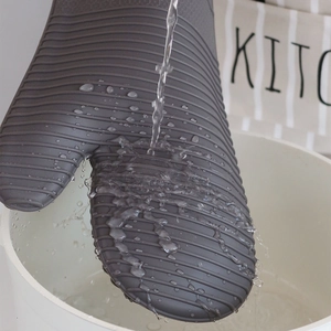 Waterproof grey silicone oven mitt being rinsed under water with non-slip texture