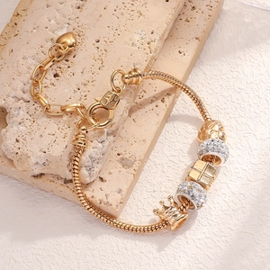 Golden charm bracelet with crown heart pendants and sparkling stones on snake chain