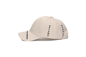 Detail showing beige cotton baseball cap with black embroidered text on the side