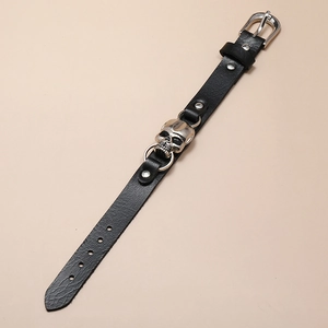 Close-up of black leather bracelet featuring silver metal skull and pin buckle detail