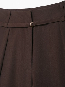 Dettaglio macro della vita di pantaloni marroni con fibbia dorata e pieghe rifinite
