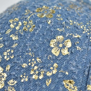 Macro view of blue denim fabric with gold foil floral pattern on a hip hop baseball cap