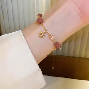 Pink strawberry quartz beaded heart bracelet with gold chain on woman's wrist