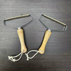 Manual wood handle lint remover with copper head for wool coats on dark wood surface