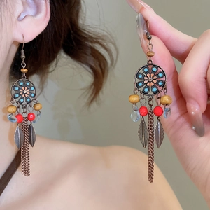 Détail de boucles d'oreilles ethniques avec motifs floraux vintage et pompons métal