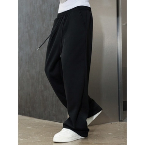 Detail of men's loose black joggers with drawstring waist and knit fabric texture