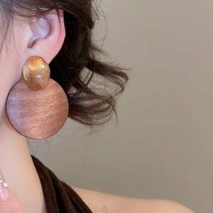 Close-up of geometric wood and amber resin drop earrings worn on a female model