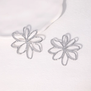 Macro detail of silver hollow floral stud earrings with high-shine metallic finish
