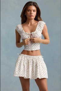 Detail of white floral crop top with puff sleeves and matching tie-up mini skirt