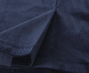 Detailed macro view of navy blue corduroy fabric showing ribbed texture and hem slit detail