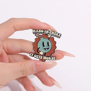 Funny enamel pin featuring a green bomb and Hang In There It Gets Worse humor slogan